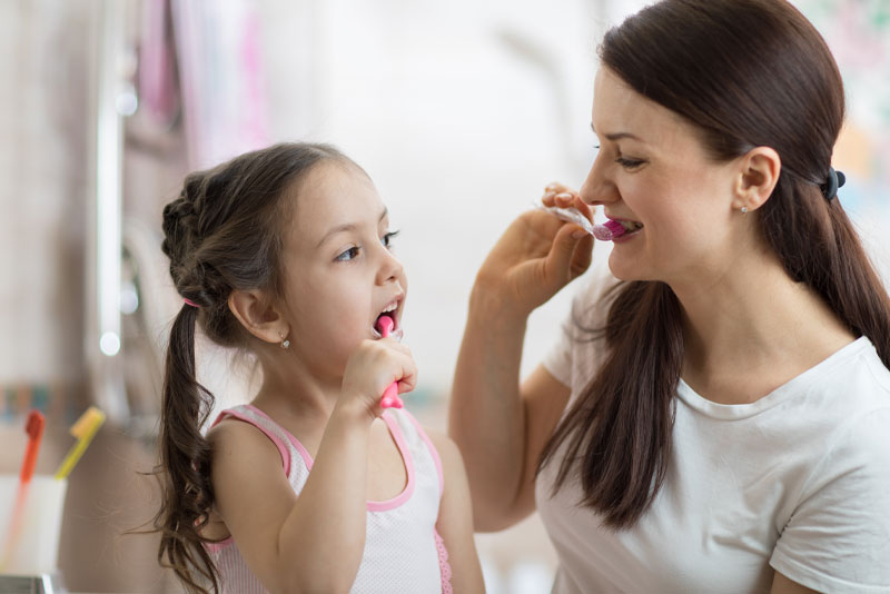 mother and daughter brushing their teeth